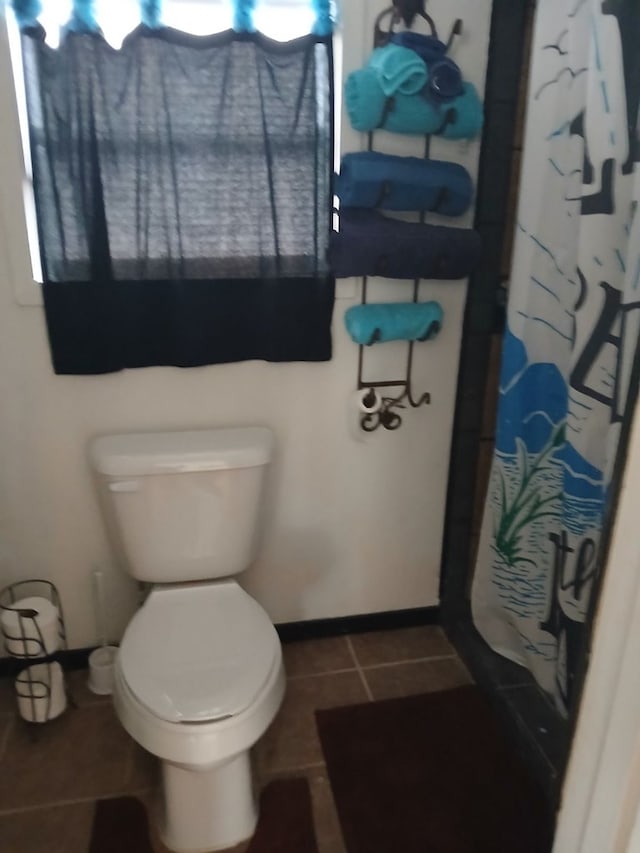 bathroom featuring toilet, tile patterned flooring, a shower with shower curtain, and baseboards