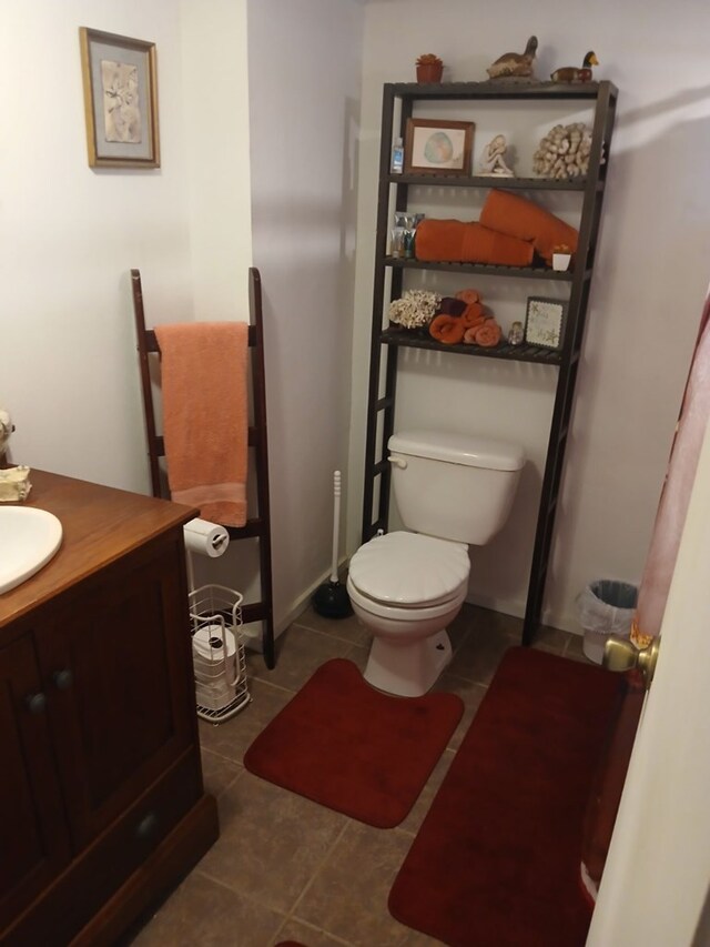 half bathroom with tile patterned floors, toilet, and vanity