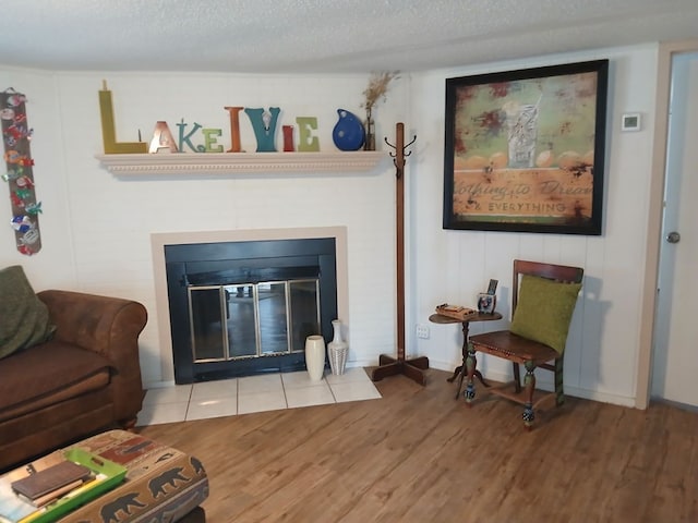 living area with a textured ceiling, baseboards, a fireplace with flush hearth, and wood finished floors