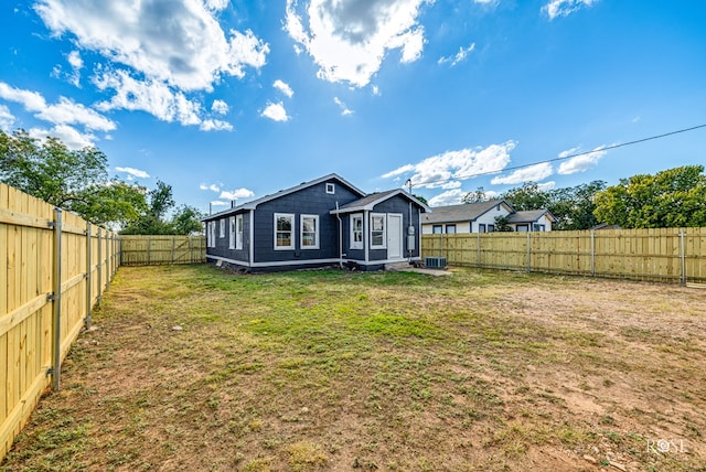 back of house featuring a fenced backyard and a lawn