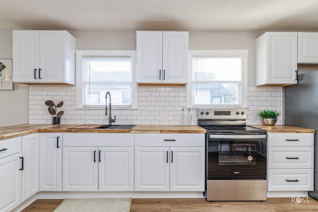 kitchen with plenty of natural light, butcher block countertops, a sink, and electric range