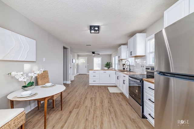 kitchen featuring a peninsula, light wood-style flooring, white cabinetry, appliances with stainless steel finishes, and a sink