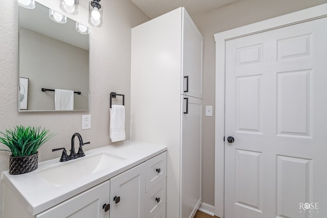 bathroom featuring a textured wall and vanity
