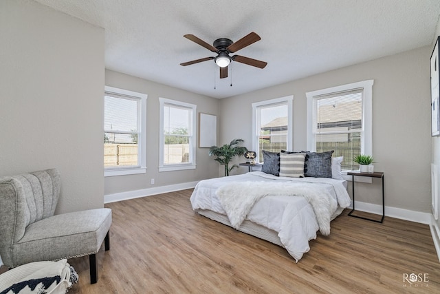 bedroom with light wood-style flooring, ceiling fan, and baseboards