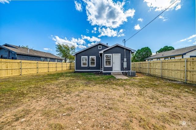 rear view of property featuring a fenced backyard, central AC, and a lawn