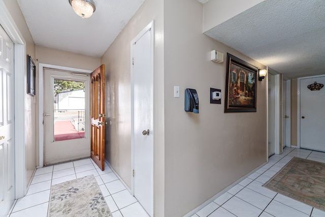 doorway to outside featuring light tile patterned floors and a textured ceiling