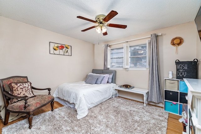 bedroom with ceiling fan, a textured ceiling, and wood finished floors