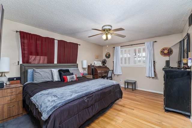 bedroom featuring a textured ceiling, ceiling fan, light wood-type flooring, and baseboards