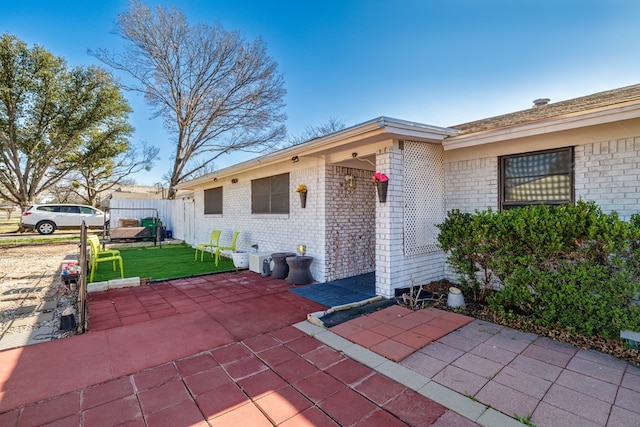 exterior space with a patio, brick siding, and fence