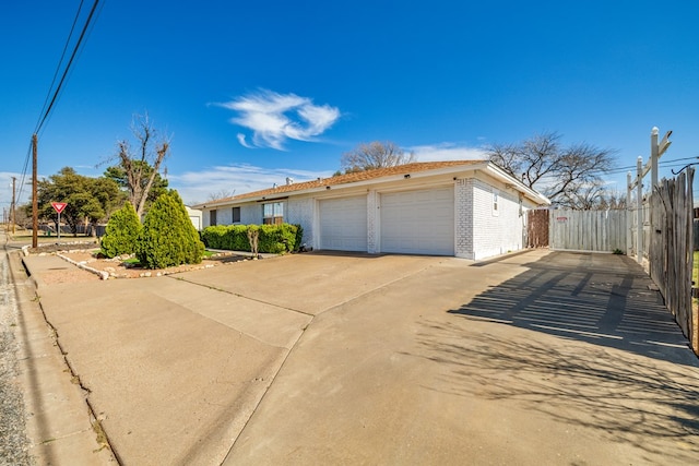 view of front of house featuring driveway, an attached garage, fence, and brick siding