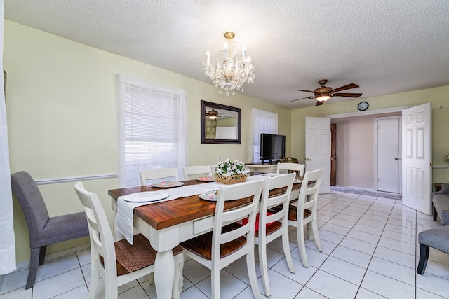 dining room with light tile patterned floors, a textured ceiling, and ceiling fan with notable chandelier