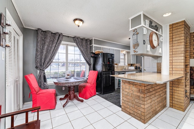 kitchen featuring crown molding, light tile patterned floors, freestanding refrigerator, a sink, and a peninsula