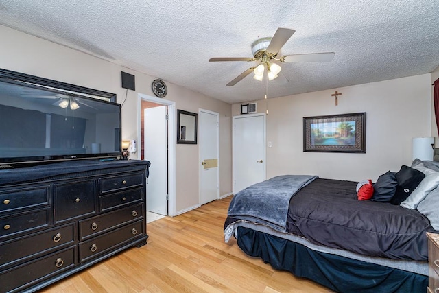 bedroom with light wood-style floors, ceiling fan, and a textured ceiling