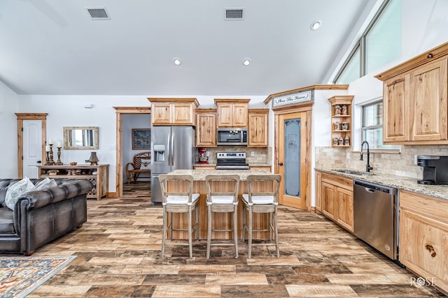 5292 Grey Wolf Ln, San Angelo, TX 76901 - kitchen with appliances with stainless steel finishes, a sink, open shelves, a kitchen bar, and light stone counters