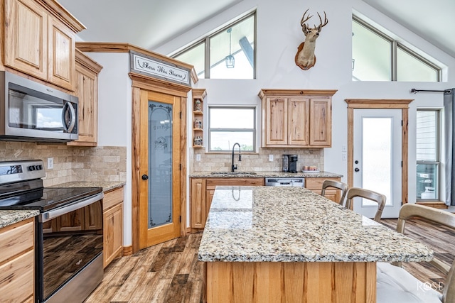 5292 Grey Wolf Ln, San Angelo, TX 76901 - kitchen with appliances with stainless steel finishes, a sink, light wood-style floors, tasteful backsplash, and a towering ceiling