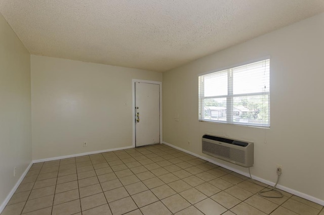 1901 Pulliam St, San Angelo, TX 76905 - empty room with a wall unit AC, a textured ceiling, baseboards, and light tile patterned floors