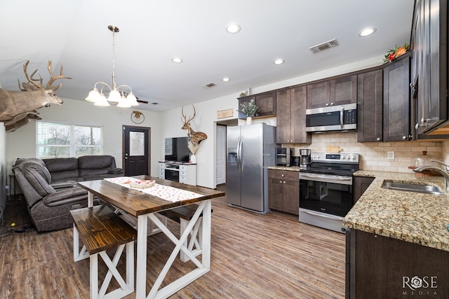 kitchen featuring dark brown cabinetry, stainless steel appliances, a sink, visible vents, and tasteful backsplash