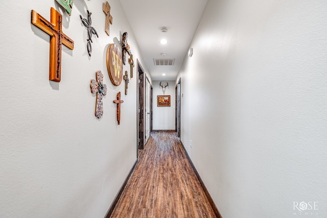 hallway featuring baseboards, visible vents, and wood finished floors