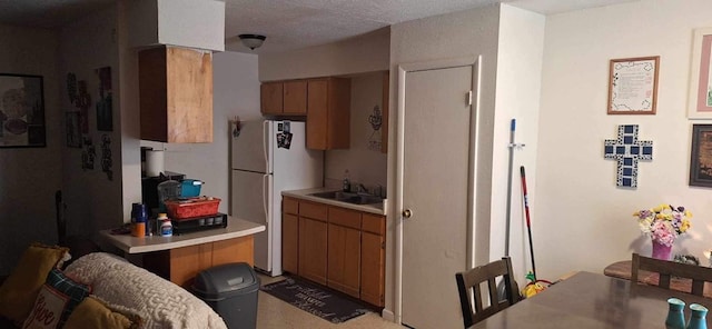 kitchen featuring white refrigerator, sink, and a textured ceiling