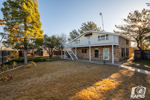 back of property featuring a wooden deck, a yard, and a patio area