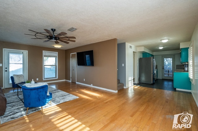 unfurnished living room featuring wood-type flooring, a textured ceiling, and ceiling fan