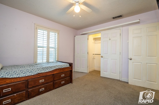 carpeted bedroom featuring ceiling fan and a textured ceiling