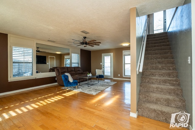 unfurnished living room featuring hardwood / wood-style flooring, ceiling fan, and a textured ceiling