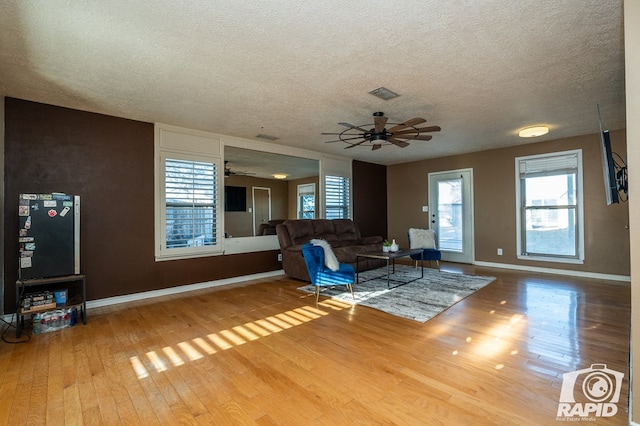 unfurnished living room featuring hardwood / wood-style flooring, a textured ceiling, and ceiling fan