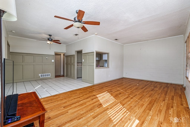 unfurnished living room with ornamental molding, brick wall, light wood-type flooring, and a textured ceiling