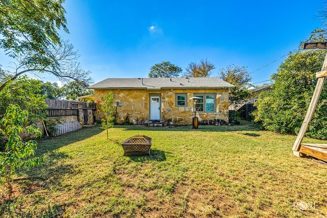 rear view of house featuring a fire pit and a lawn