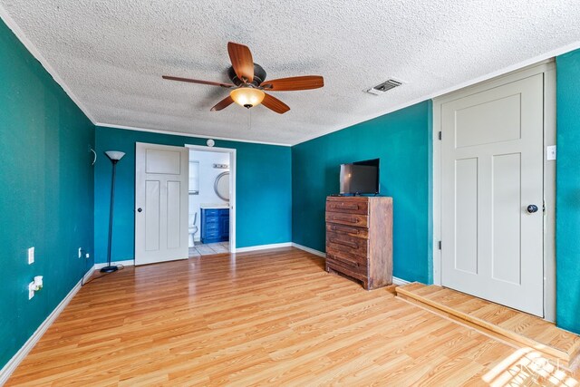 unfurnished bedroom featuring ceiling fan, ornamental molding, light wood-type flooring, and ensuite bath