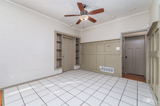 unfurnished bedroom featuring light tile patterned floors, ceiling fan, ornamental molding, a textured ceiling, and a closet