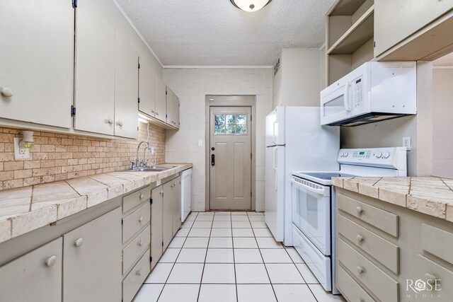 kitchen featuring sink, a textured ceiling, light tile patterned floors, ornamental molding, and white appliances