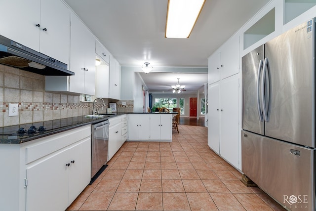 3237 Red Bluff Rd W, San Angelo, TX 76904 - kitchen with appliances with stainless steel finishes, extractor fan, dark countertops, a peninsula, and decorative backsplash