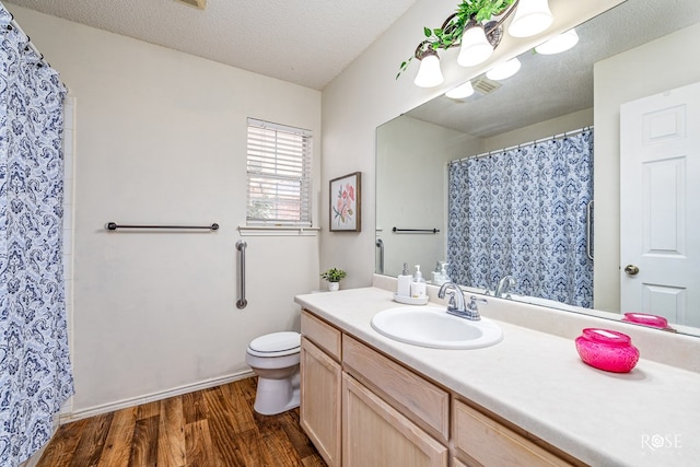 5221 Coral Way, San Angelo, TX 76904 - full bathroom with wood finished floors, toilet, vanity, a textured ceiling, and curtained shower