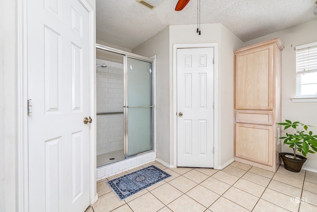 5221 Coral Way, San Angelo, TX 76904 - bathroom with ceiling fan, a shower stall, tile patterned floors, a textured ceiling, and baseboards