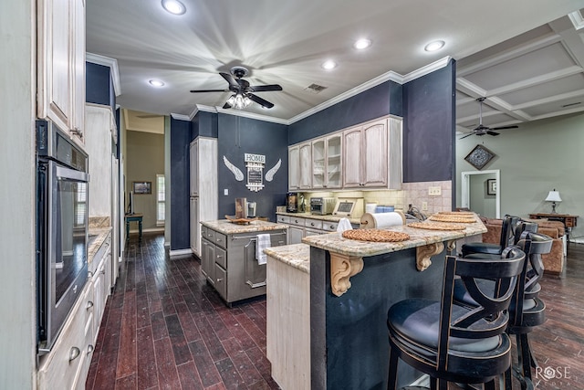 3122 Clearview Dr, San Angelo, TX 76904 - kitchen with a ceiling fan, a kitchen island, stainless steel oven, a kitchen breakfast bar, and light stone countertops