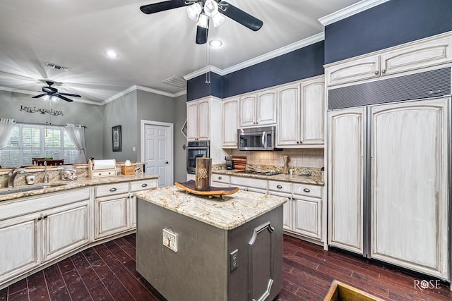 3122 Clearview Dr, San Angelo, TX 76904 - kitchen with stainless steel appliances, a ceiling fan, dark wood-style flooring, ornamental molding, and backsplash