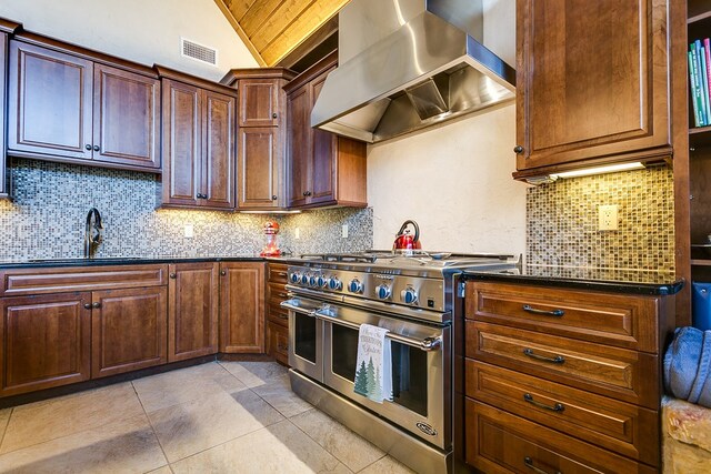 kitchen with double oven range, sink, exhaust hood, and decorative backsplash