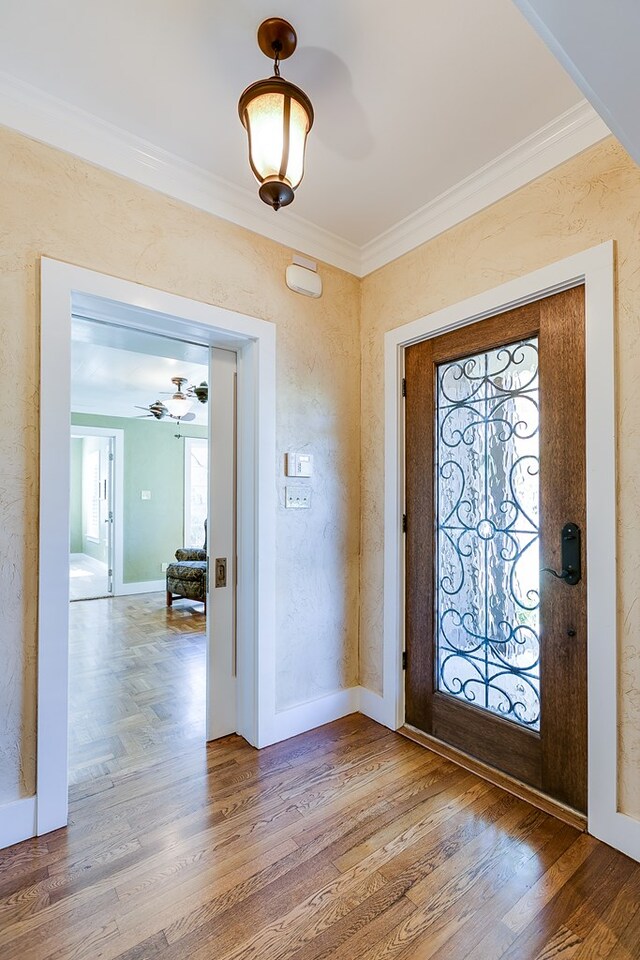 foyer entrance with hardwood / wood-style floors and crown molding