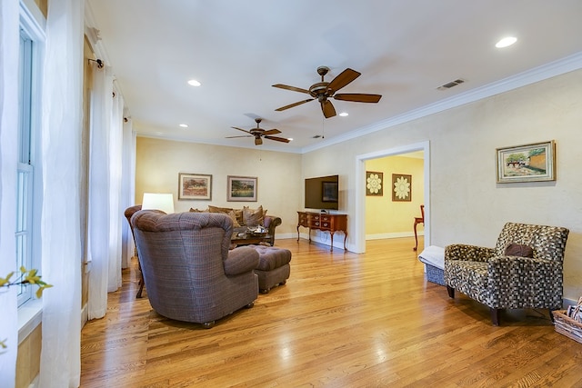 living room featuring ceiling fan, ornamental molding, and light wood-type flooring