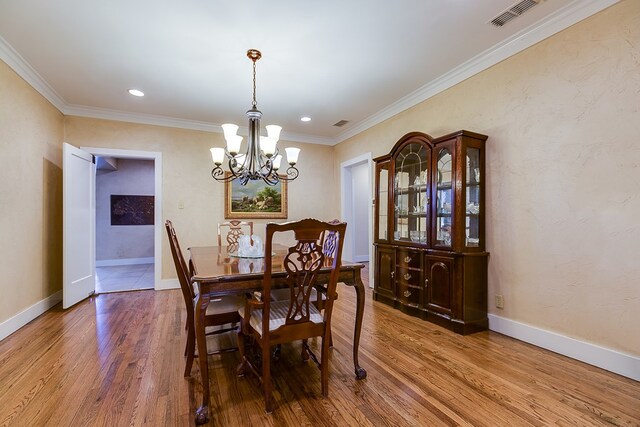 dining area featuring wood-type flooring, ornamental molding, and a chandelier