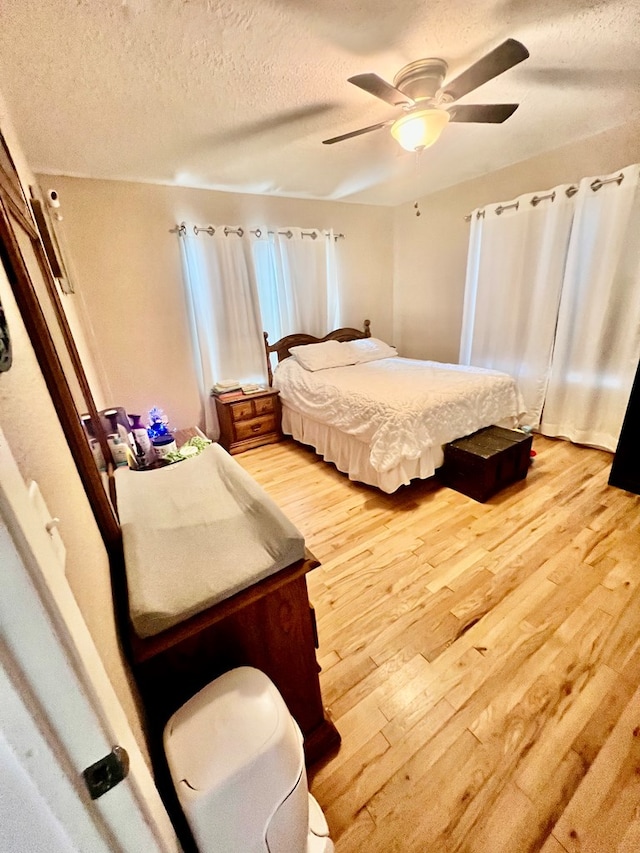 bedroom featuring hardwood / wood-style flooring, ceiling fan, and a textured ceiling