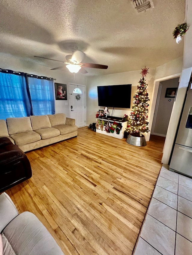 tiled living room with ceiling fan and a textured ceiling