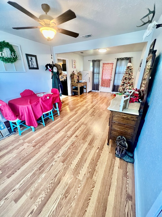 interior space featuring a textured ceiling, light hardwood / wood-style flooring, and ceiling fan