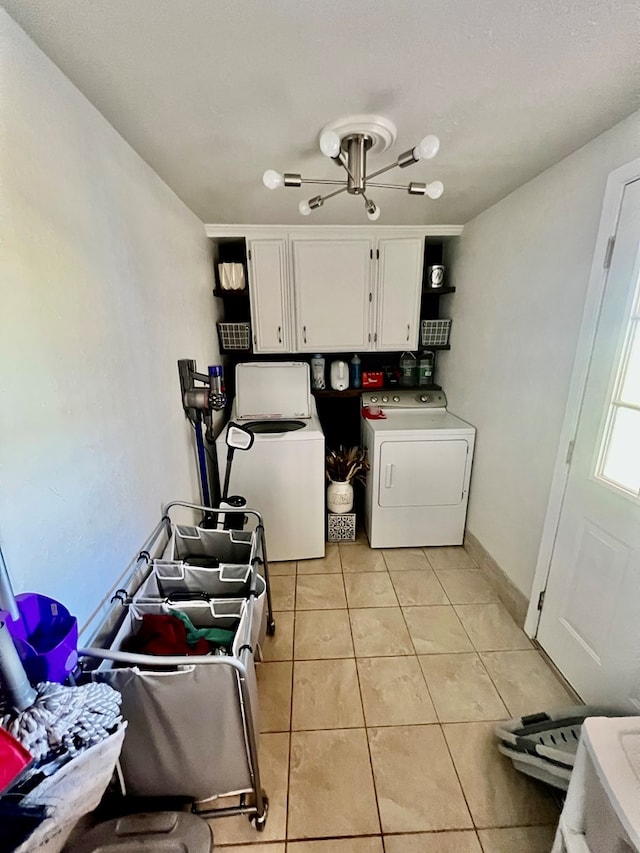 clothes washing area featuring cabinets, light tile patterned flooring, and washing machine and dryer