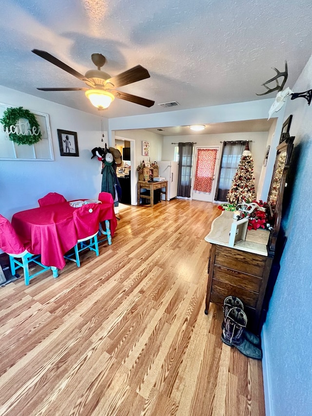 living room featuring wood-type flooring, ceiling fan, and a textured ceiling