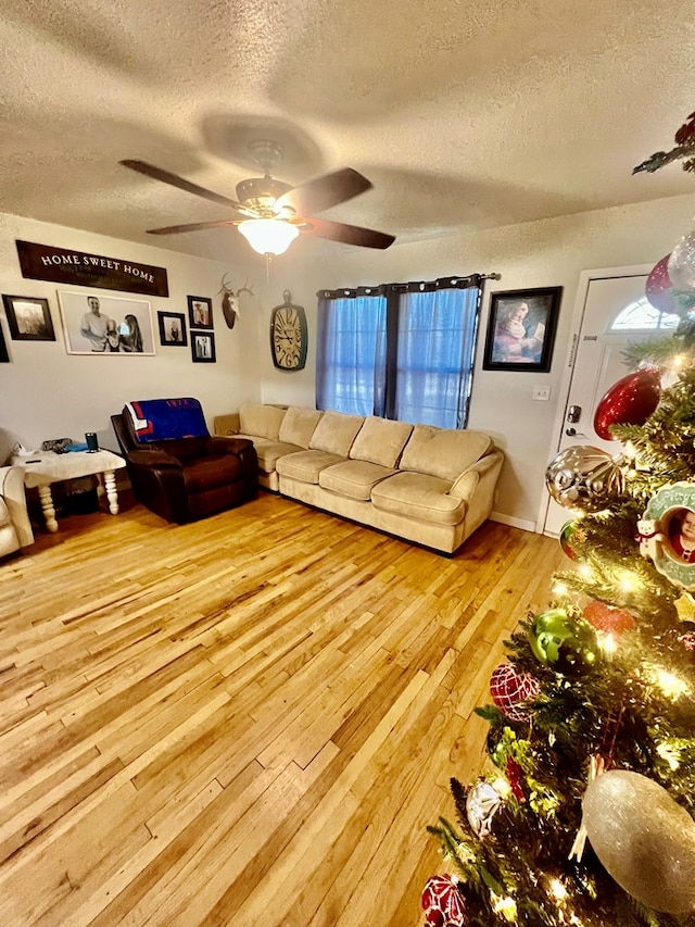 living room featuring ceiling fan, a textured ceiling, and light wood-type flooring