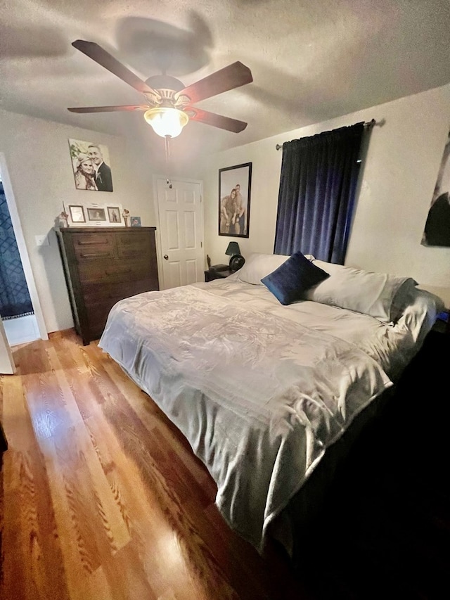 bedroom with a textured ceiling, ceiling fan, and light hardwood / wood-style flooring