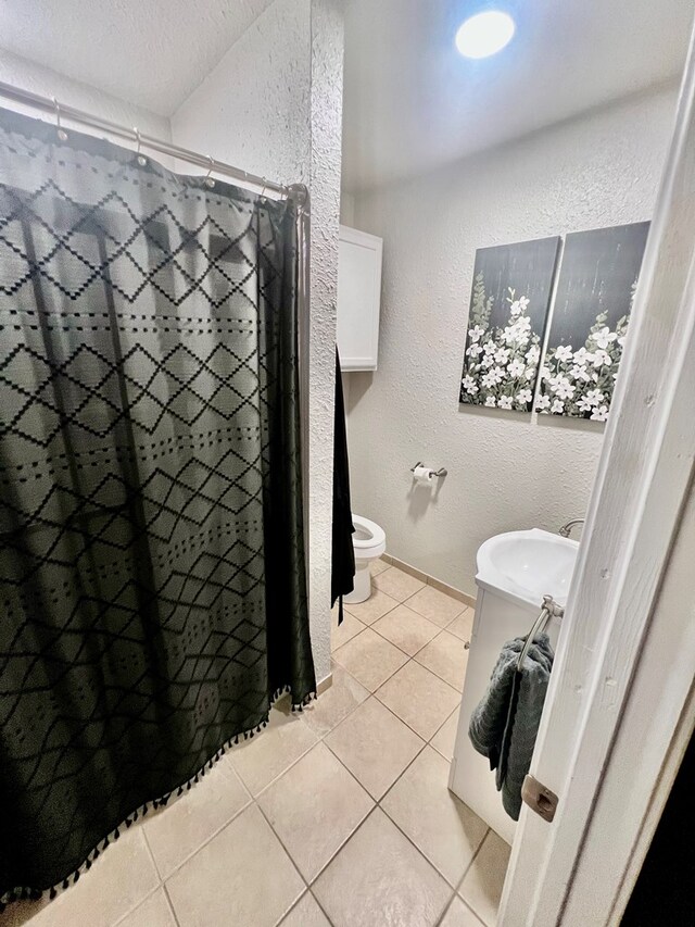 bathroom featuring sink, tile patterned flooring, toilet, a textured ceiling, and a shower with shower curtain